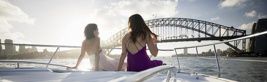 シドニー・ハーバーで帆走するヨットの前の2人の女性